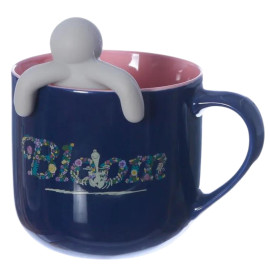 Caneca de cermica azul escura com o interior rosa, com a palavra "Bloom" decorada com flores coloridas e acompanhada de um mini boneco branco que se encaixa na borda da caneca, proporcionando um toque divertido e relaxante.